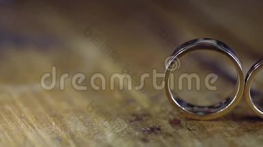 木质地板上的金色结婚戒指，背光的宏观特写镜头，耀斑，钻石首饰